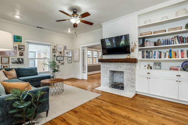 living room featuring a fireplace, ornamental molding, light hardwood / wood-style floors, and ceiling fan