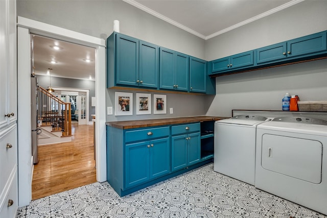 clothes washing area featuring crown molding, independent washer and dryer, and cabinets