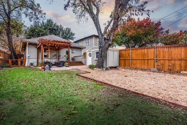 back house at dusk featuring a storage unit, a yard, a pergola, and a patio