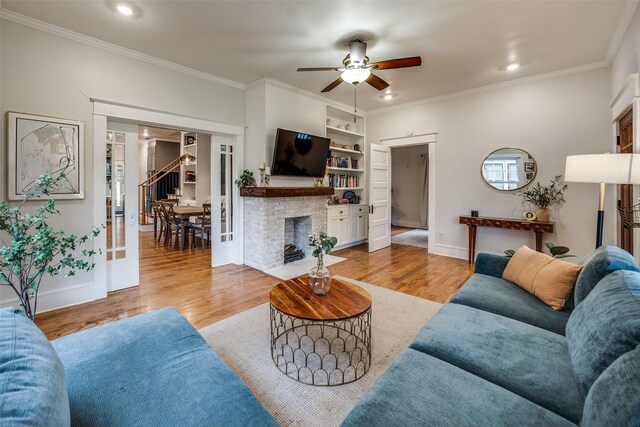 living room with crown molding, light hardwood / wood-style floors, and a brick fireplace