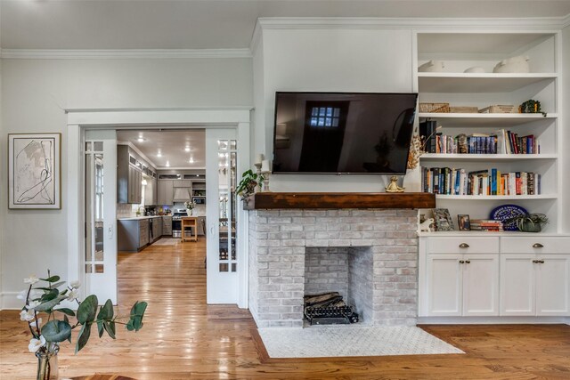 living room with crown molding, a brick fireplace, and light hardwood / wood-style flooring