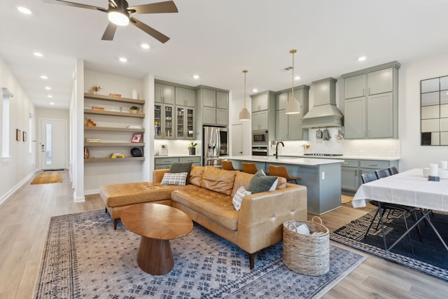 living area featuring baseboards, light wood finished floors, and recessed lighting