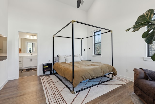 bedroom with high vaulted ceiling, a sink, and light wood finished floors