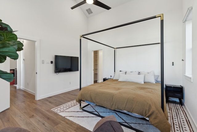 bedroom with high vaulted ceiling, baseboards, visible vents, and wood finished floors