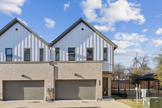 view of front of home with driveway, brick siding, board and batten siding, and fence