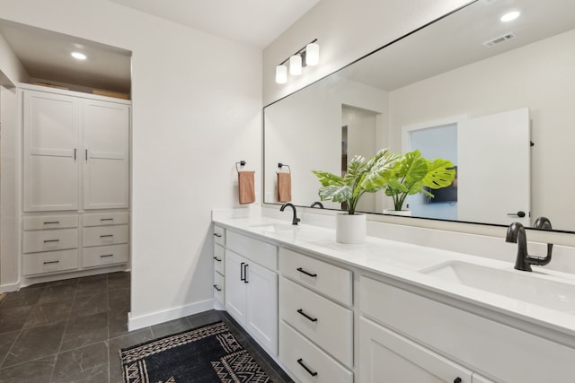 bathroom featuring recessed lighting, a sink, baseboards, and double vanity