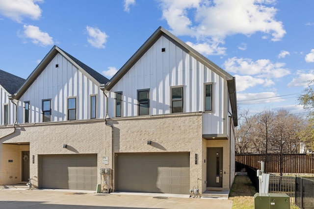 view of front of home featuring a garage, fence, board and batten siding, and brick siding