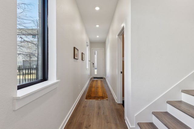 corridor with stairway, baseboards, wood finished floors, and recessed lighting