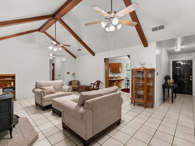 living room with light tile patterned floors, beam ceiling, ceiling fan, and a wood stove