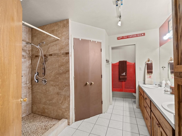 bathroom with tile patterned flooring, vanity, and a tile shower