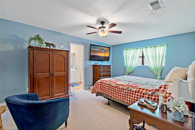 bedroom with ensuite bathroom, light carpet, a textured ceiling, and ceiling fan