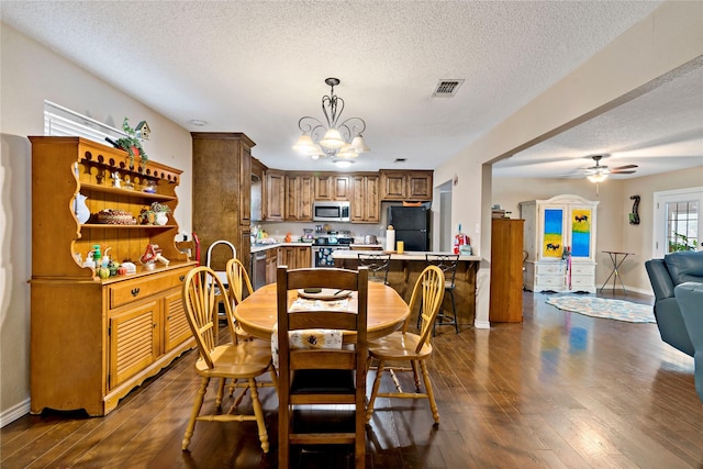 dining area featuring dark hardwood / wood-style floors, ceiling fan with notable chandelier, and a textured ceiling