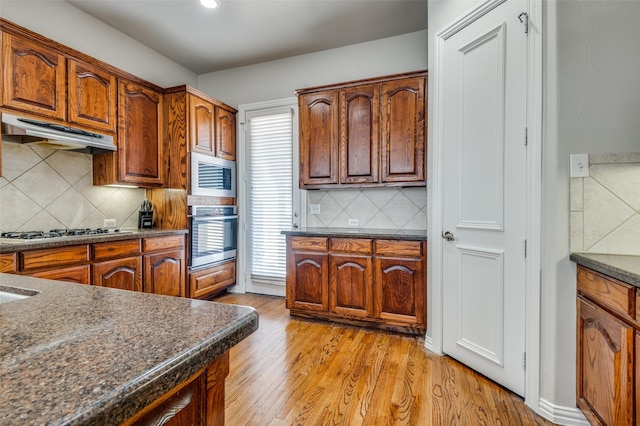 kitchen featuring tasteful backsplash, light hardwood / wood-style floors, and appliances with stainless steel finishes