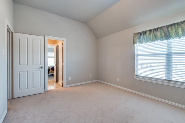 unfurnished bedroom featuring multiple windows, lofted ceiling, and light carpet