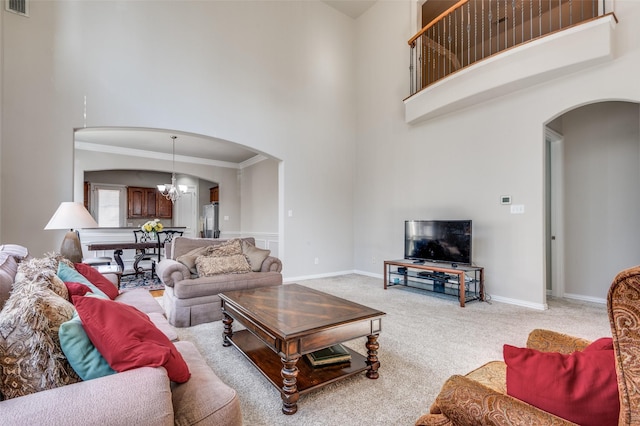 carpeted living room with a high ceiling, ornamental molding, and a notable chandelier