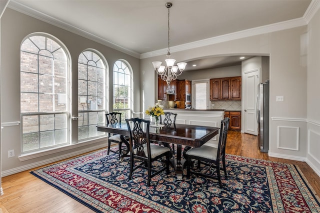 dining area featuring ornamental molding, hardwood / wood-style floors, and a notable chandelier