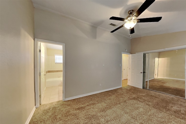 unfurnished bedroom featuring ceiling fan, carpet floors, ensuite bath, and a closet