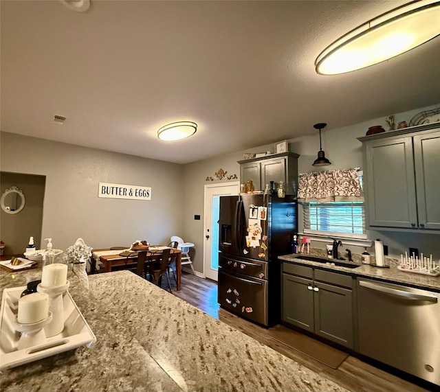 kitchen featuring pendant lighting, sink, dark hardwood / wood-style floors, light stone countertops, and stainless steel dishwasher