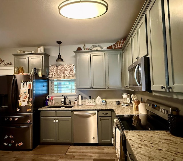 248 Mill, Emory, TX 75440 - kitchen featuring stainless steel appliances, a sink, wood finished floors, light stone counters, and gray cabinets