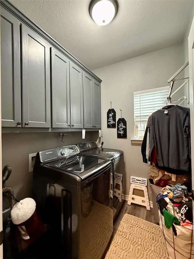 clothes washing area featuring cabinets, dark wood-type flooring, a textured ceiling, and washer and clothes dryer