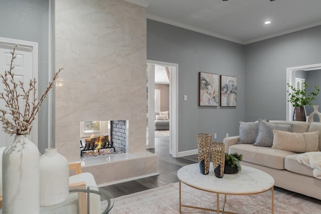 living area featuring ornamental molding, a tiled fireplace, wood finished floors, recessed lighting, and baseboards