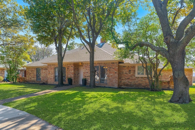 ranch-style home with a front lawn, brick siding, and roof with shingles