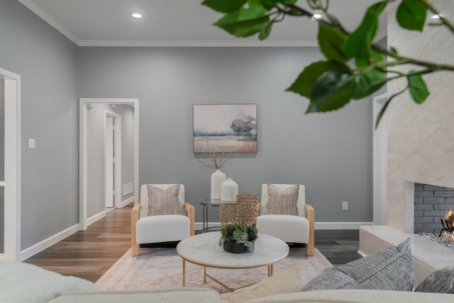 living area with baseboards, a premium fireplace, ornamental molding, recessed lighting, and wood finished floors