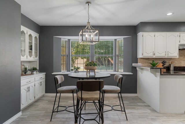 kitchen featuring white cabinetry, stainless steel refrigerator, kitchen peninsula, pendant lighting, and decorative backsplash