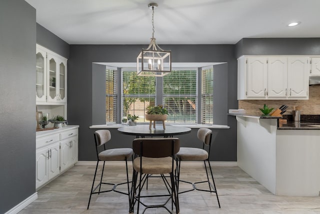 dining space featuring baseboards, light wood-style floors, and an inviting chandelier