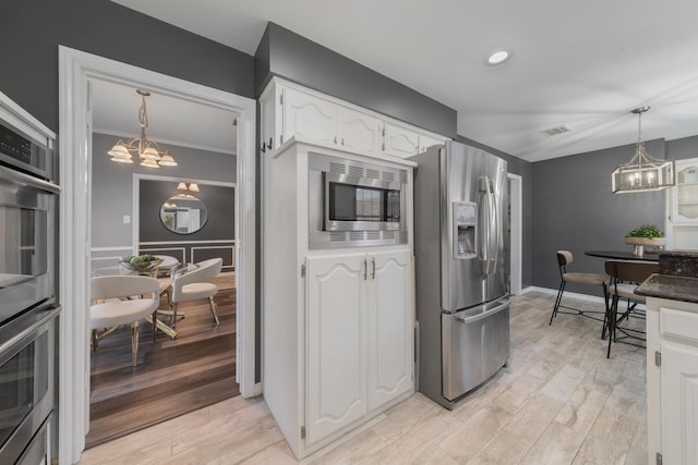 kitchen featuring visible vents, decorative light fixtures, stainless steel appliances, light wood-style floors, and white cabinets