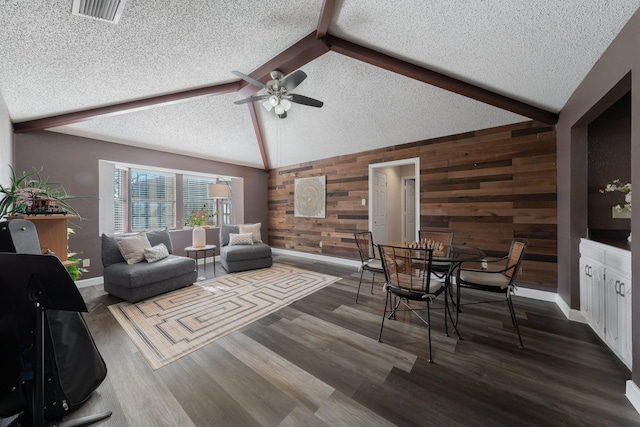 living room featuring dark wood-type flooring, a textured ceiling, and wood walls