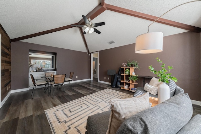 living area with a ceiling fan, a textured ceiling, wood finished floors, baseboards, and vaulted ceiling with beams