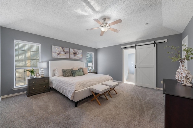 carpeted bedroom with ceiling fan, a barn door, and a textured ceiling