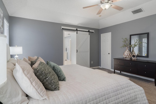 bedroom with visible vents, baseboards, a barn door, vaulted ceiling, and carpet flooring