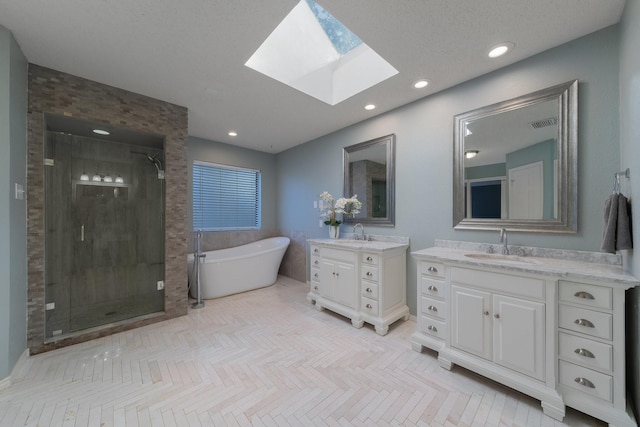 full bath with tile patterned floors, a sink, a skylight, a shower stall, and a freestanding bath