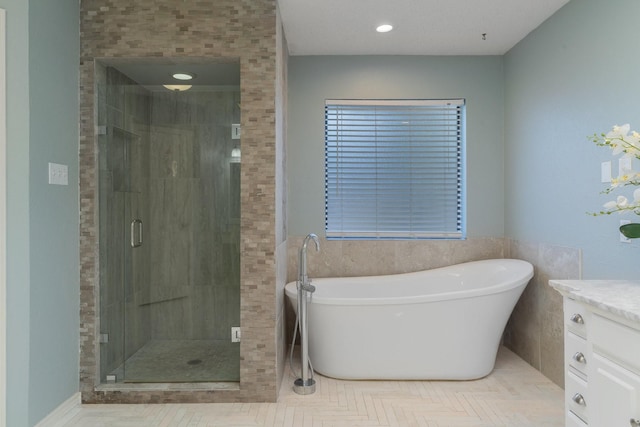 bathroom featuring vanity, a shower stall, a freestanding tub, and recessed lighting