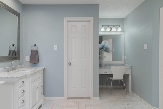 bathroom with a textured ceiling, vanity, and baseboards