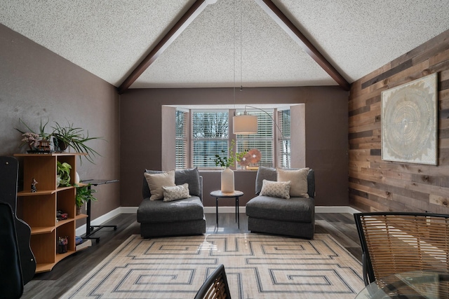 living area featuring wooden walls, wood finished floors, vaulted ceiling with beams, and a textured ceiling