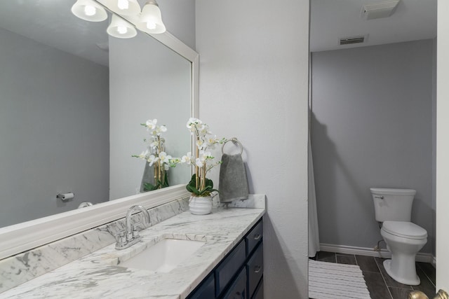 bathroom featuring vanity, toilet, visible vents, and baseboards