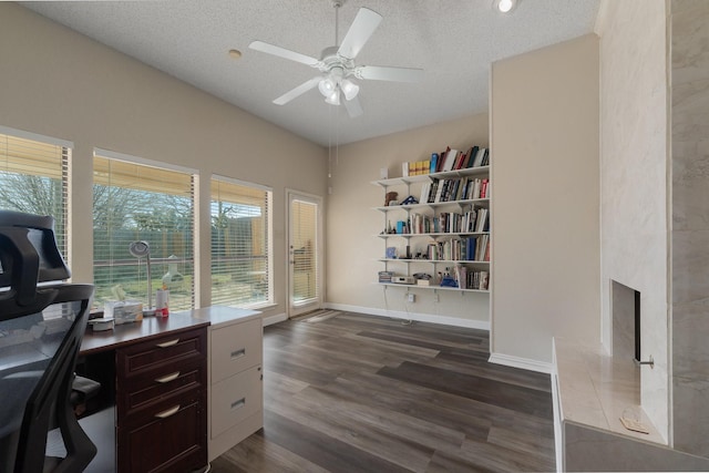 office area with a high end fireplace, baseboards, dark wood finished floors, a textured ceiling, and a ceiling fan