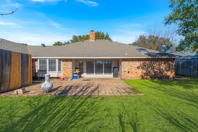 rear view of house with brick siding, a fenced backyard, a lawn, and a patio