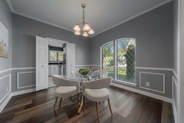 dining area featuring dark wood finished floors, a notable chandelier, crown molding, and a wainscoted wall