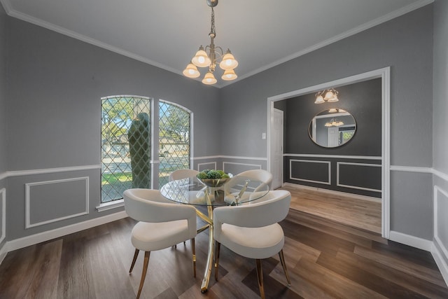 dining space with a decorative wall, ornamental molding, an inviting chandelier, and wood finished floors