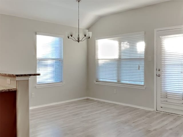 unfurnished dining area featuring vaulted ceiling, light hardwood / wood-style floors, and a chandelier