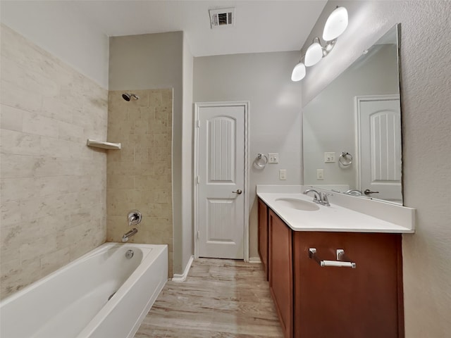 bathroom with tiled shower / bath, wood-type flooring, and vanity