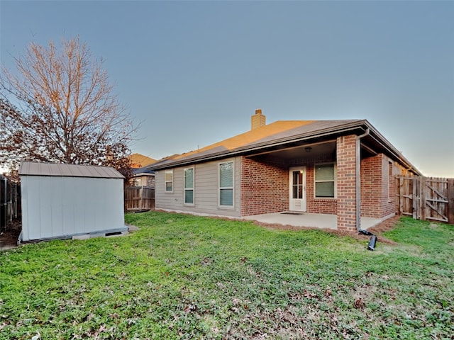 rear view of house with a yard, a patio, and a storage unit