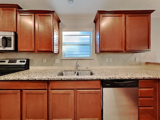 kitchen featuring tasteful backsplash, light stone countertops, appliances with stainless steel finishes, and sink