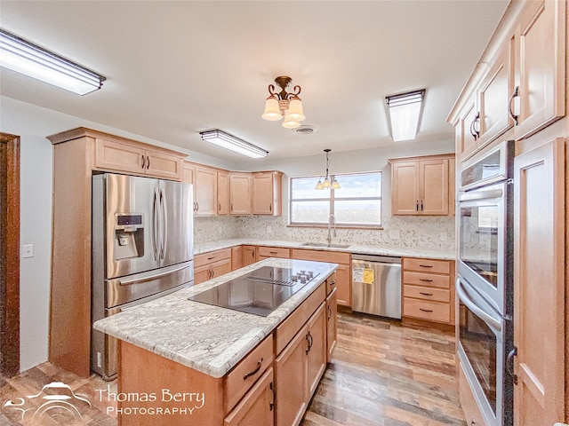 kitchen with appliances with stainless steel finishes, sink, a center island, pendant lighting, and decorative backsplash