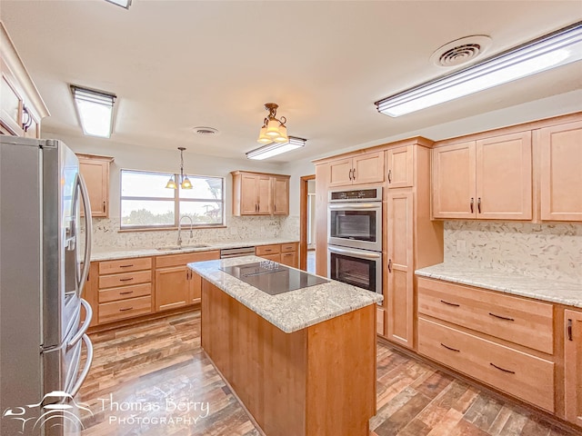 kitchen featuring sink, pendant lighting, a kitchen island, light hardwood / wood-style floors, and stainless steel appliances