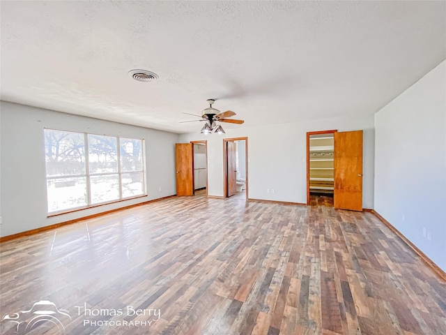 empty room with ceiling fan, wood-type flooring, and a textured ceiling